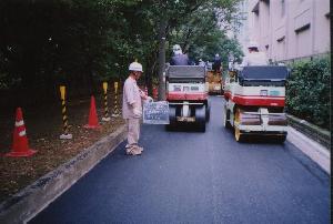 ローラー車でアスファルトを締め固めている写真