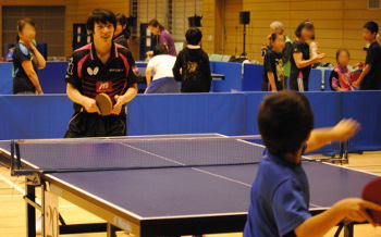 トップ選手と少年が卓球をしている写真