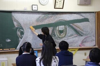 写真：すずきらなさんが黒板アート作品を消す様子